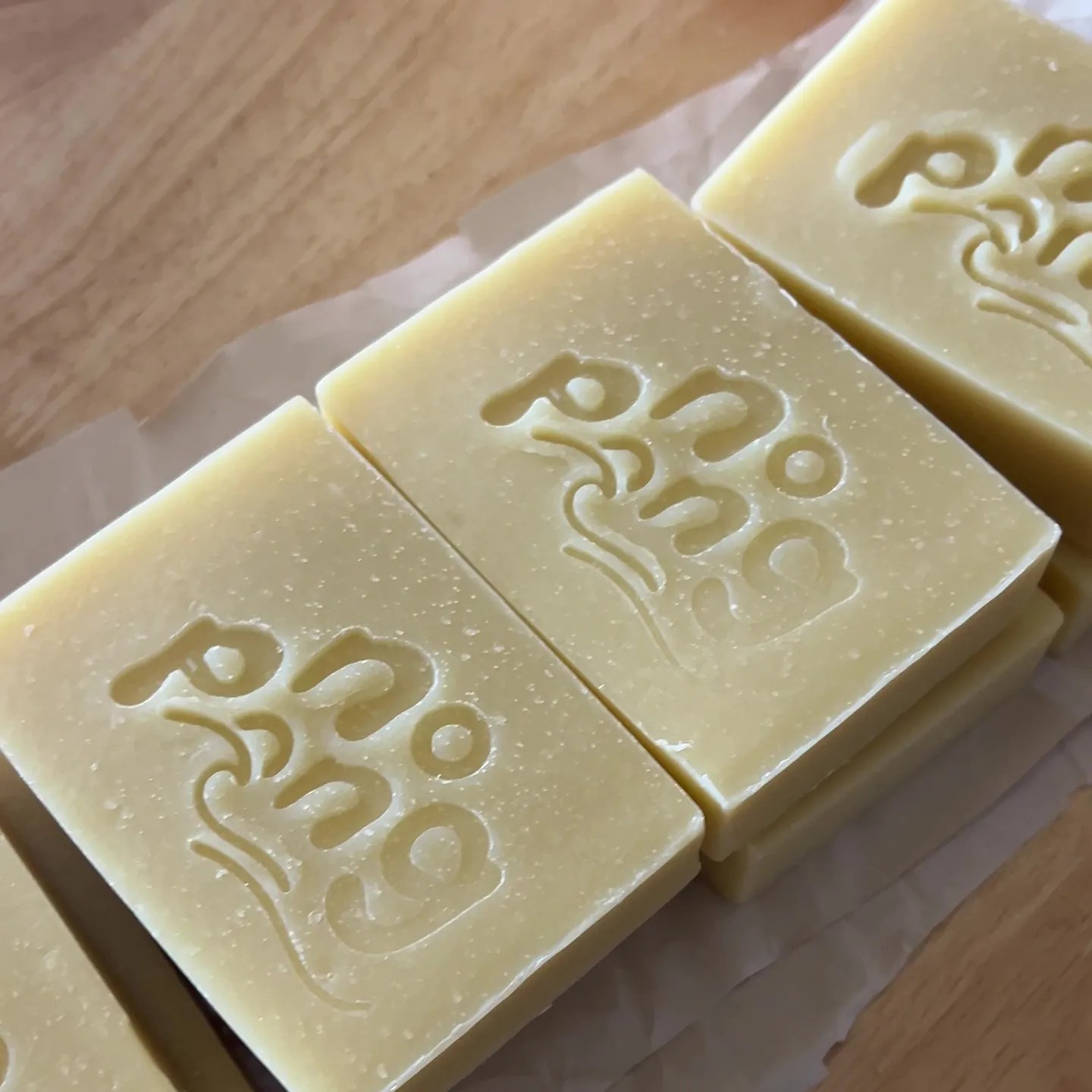 Three freshly stamped No Pong soap bars on baking paper on a wooden bench