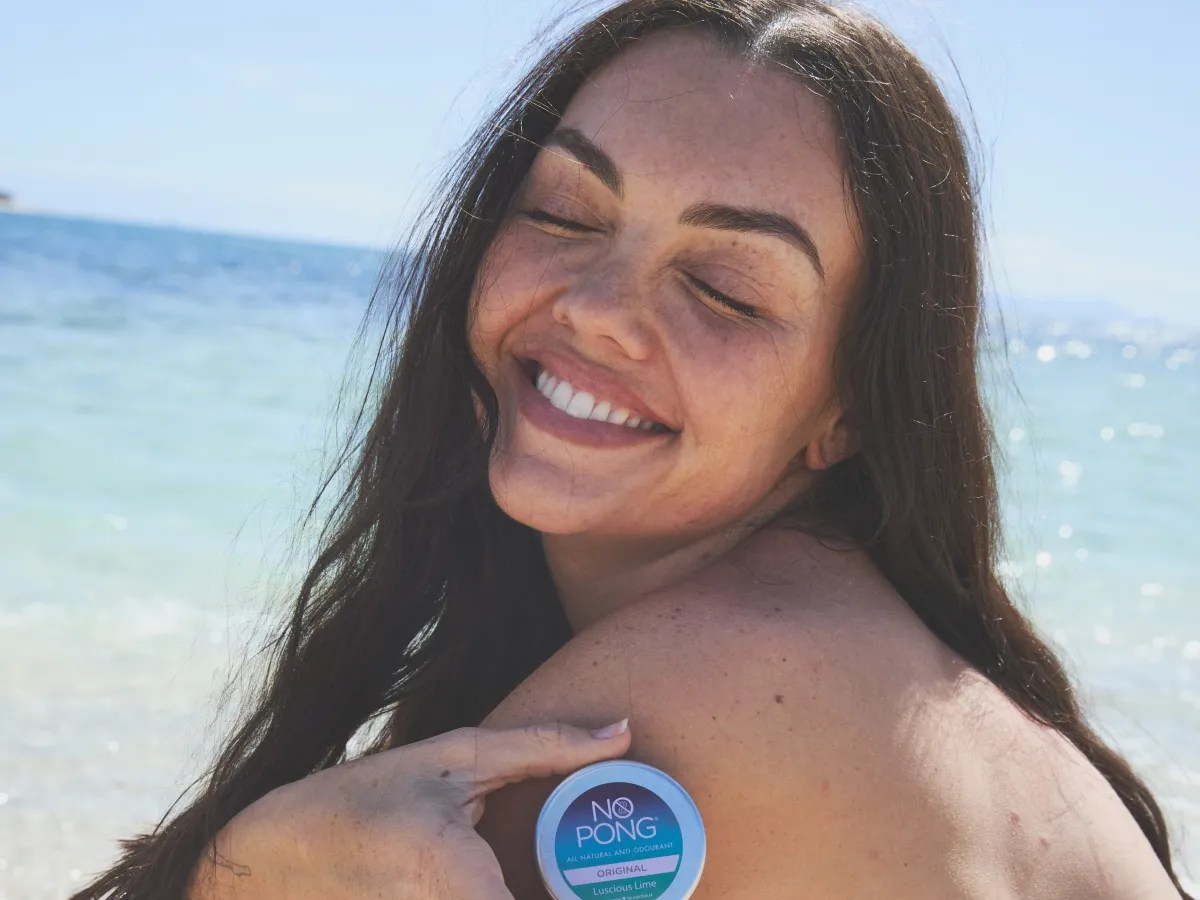 A No Pong customer smiling on the beach, her tin on her shoulder